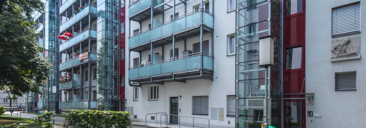 Wohnungen mit Balkonen im sanierten Gemeindebau Kapaunplatz, davor eine grüne Wiese