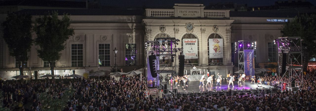 Bühne mit Tanz und Publikum im Haupthof des Museumsquartiers bei Nacht.