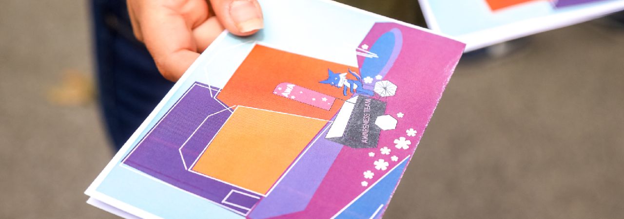 Hand mit Informationsfolder der Awareness-Teams