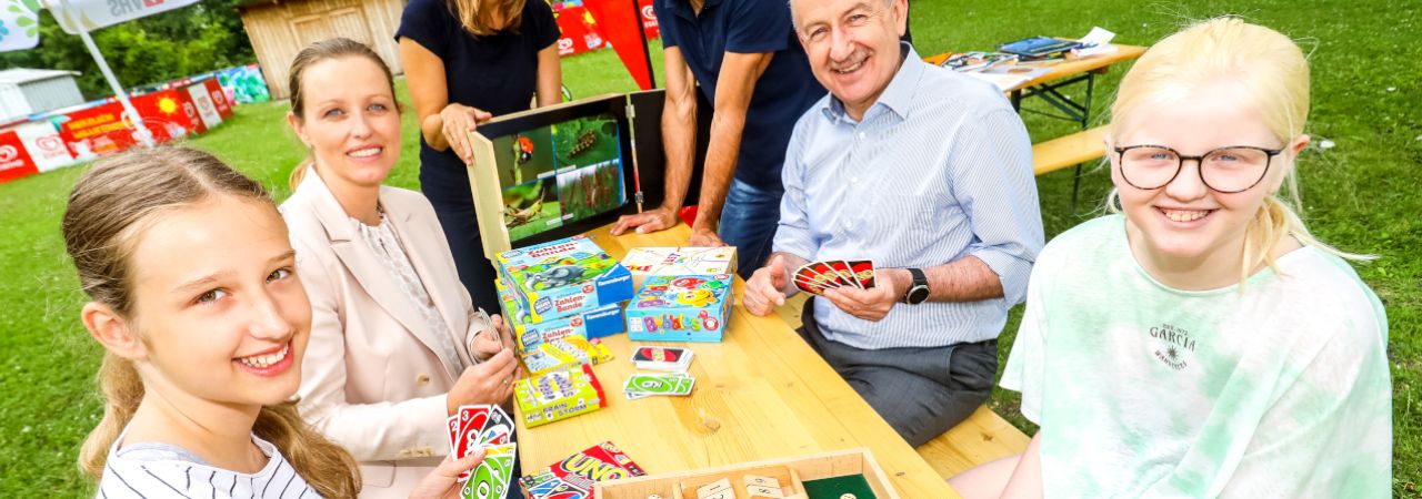 Zwei Mädchen, eine erwachsene Frau und ein erwachsener Mann sitzen an einem Tisch mit Spielen.