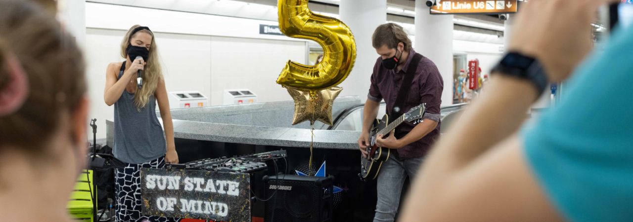 Eine Sängerin und ein Gitarrist spielen in einer U-Bahn-Station