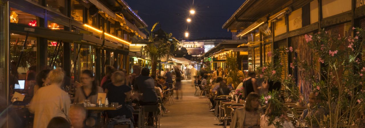 Menschen sitzen am Abend im Außenbereich von Restaurants am Naschmarkt