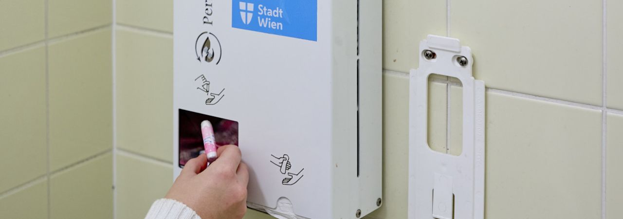 Ein Tampon wird aus dem Hygieneautomaten entnommen.