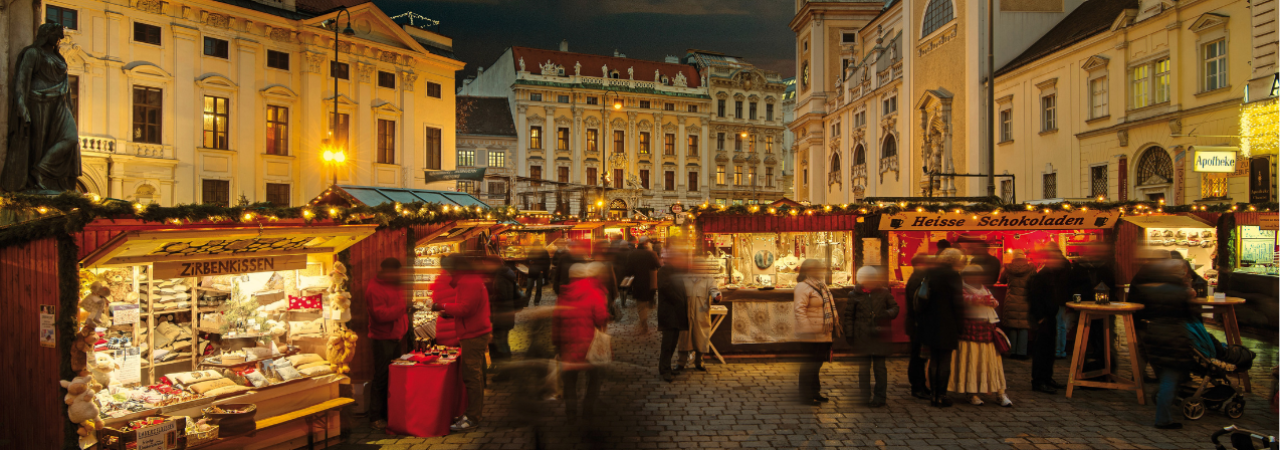 Návštěvníci a stánky na vídeňském vánočním trhu Altwiener Christkindlmarkt po setmění