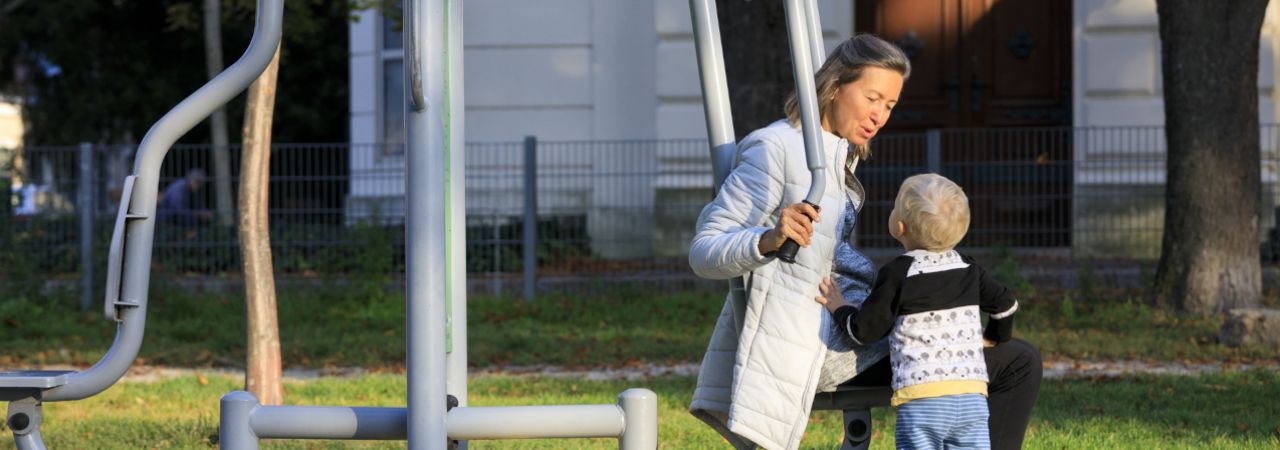 Frau und Kind auf Sportgerät in einem Park