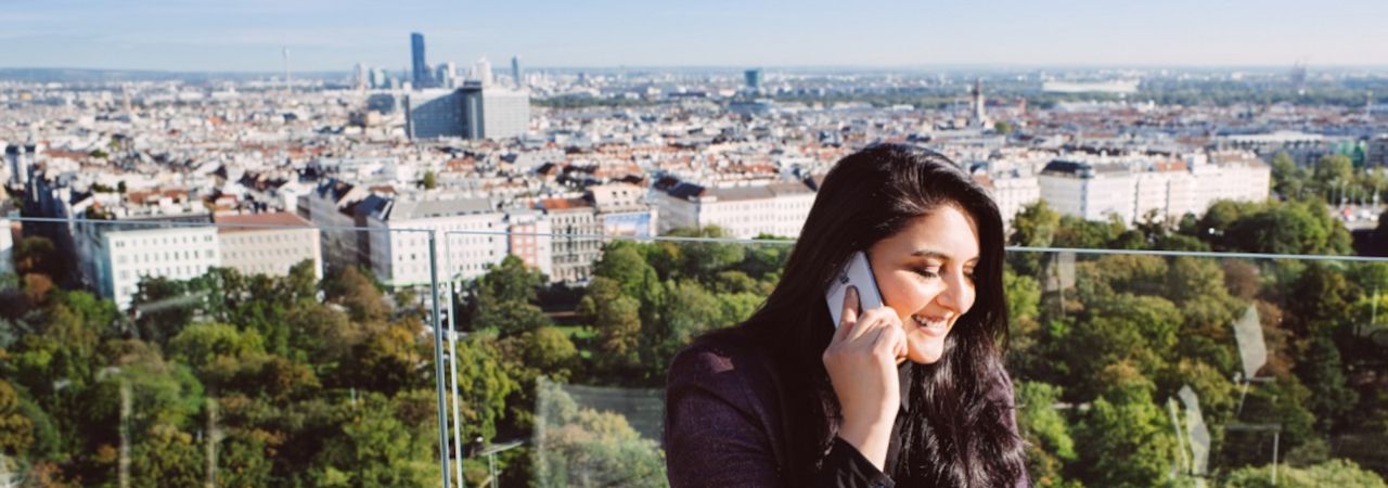 Nő telefonál, háttérben bécsi látkép