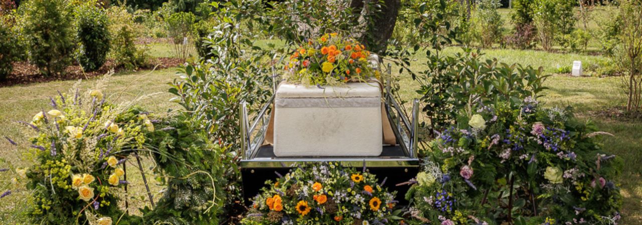'Lebender Sarg' inmitten von Blumenkränzen