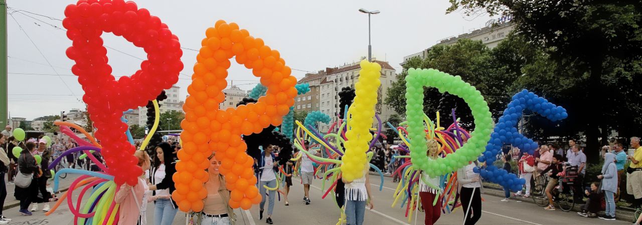 Die Buchstaben P,R,I,D,E werden aus Luftballons geformt bei der Regebogenparade getragen