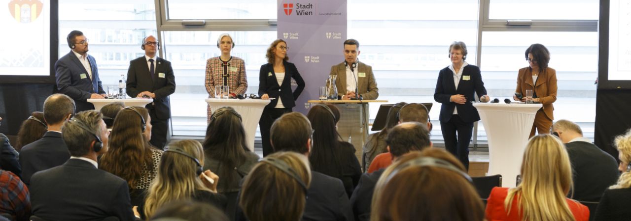 Vortragende auf dem Panel, davor Publikum