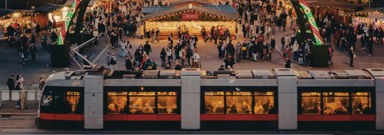 Straßenbahn fährt an Christkindlmarkt vorbei.