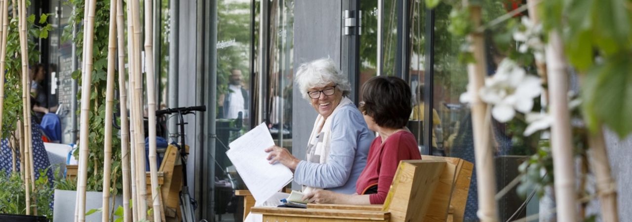 Két idős nő beszélget egy kávézó előtt