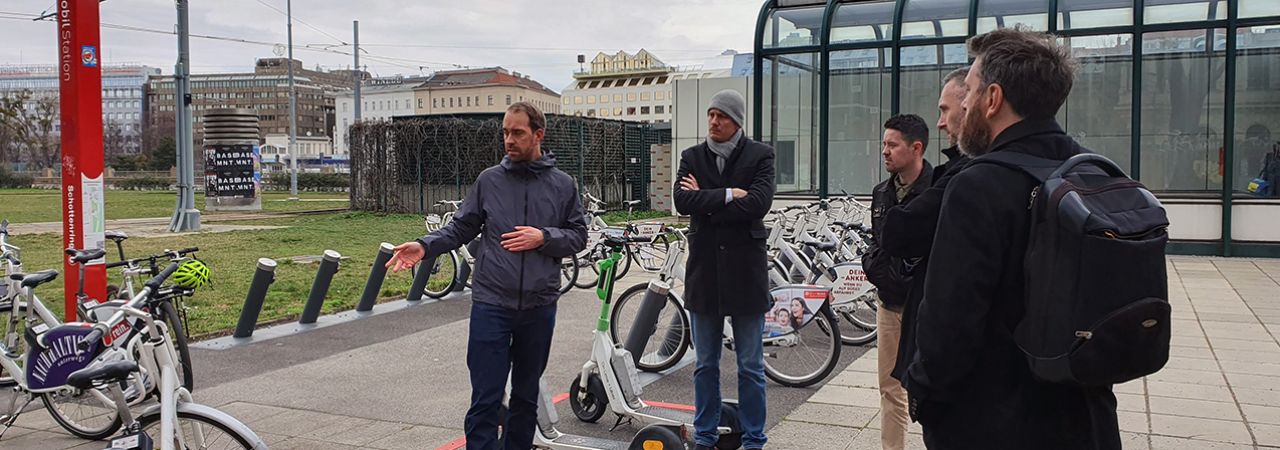 Petorica muškaraca razgledava stanicu za unajmljivanje bicikala