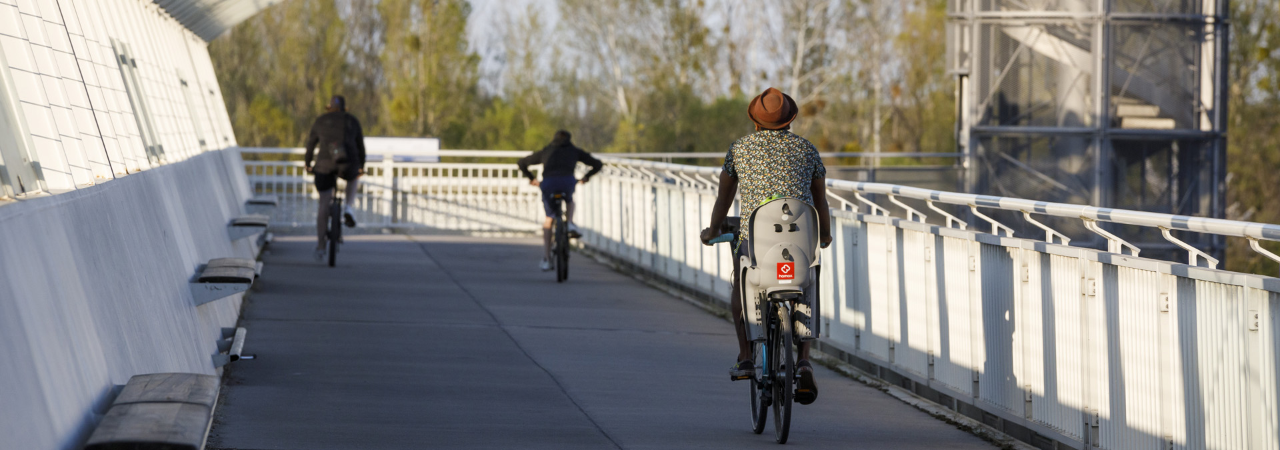 Fahrradfahrer mit Kindersitz fährt über eine Brücke