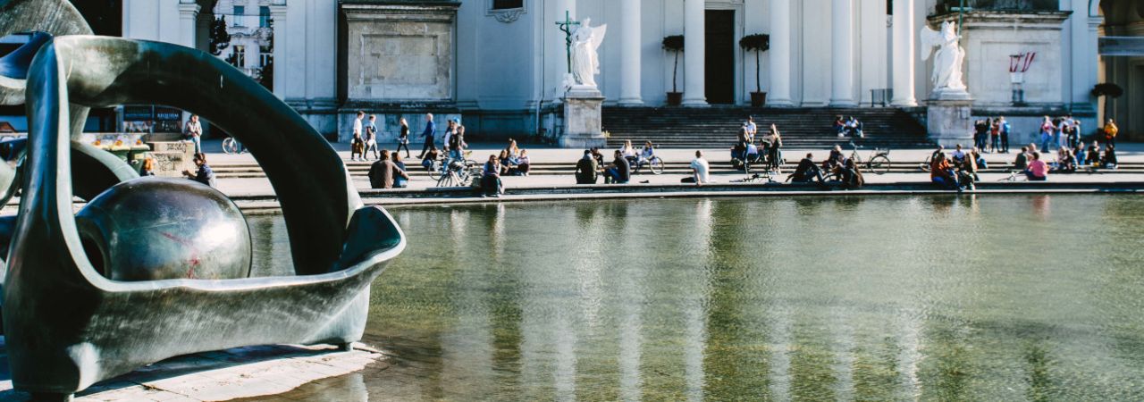 Menschen sitzen am Brunnen des Wiener Karlsplatzes