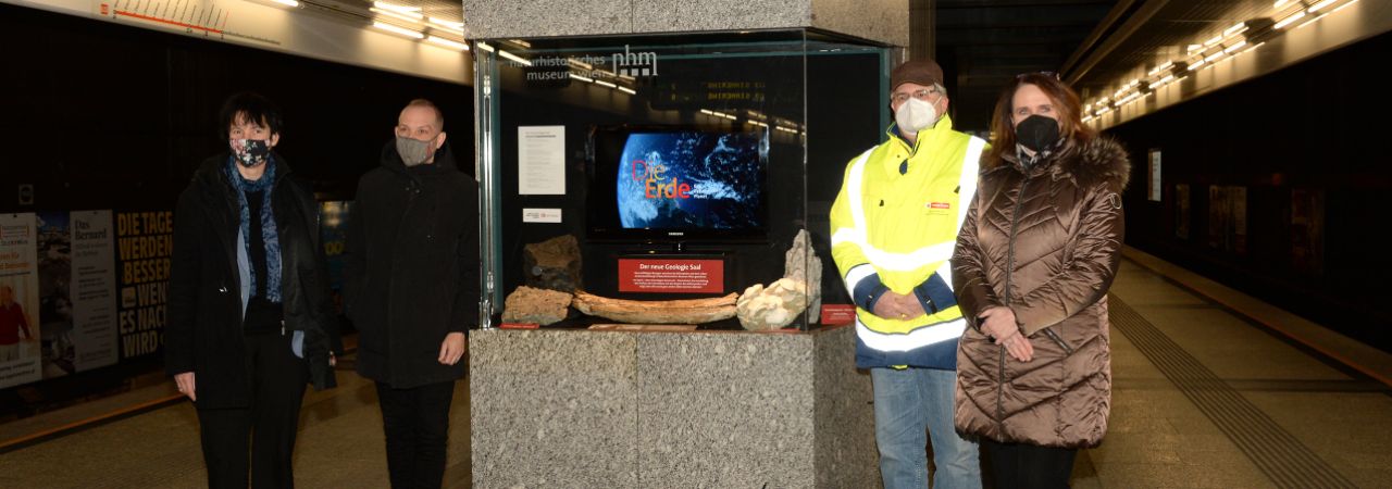 četiri osobe stoje pored vitrine sa izloženim objektom