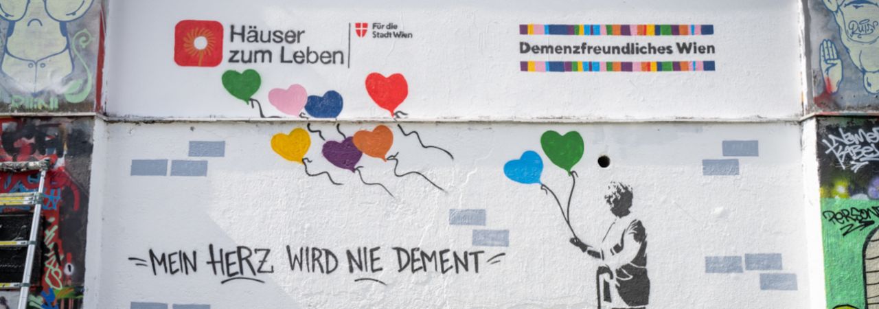 Graffiti mit der Silhouette einer betagten Dame mit Luftballons und dem Schriftzug 'Mein Herz wird nie dement'.