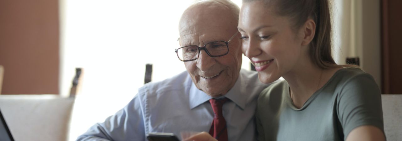 stariji gospodin i mlada djevojka zajedno gledaju u mobitel