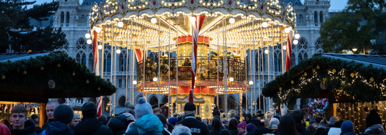 svjetleći vrtuljak na božićnom sajmu u Beču i brojni posjetitelji