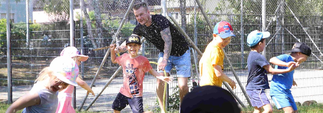 Възпитател играе на двора с деца от детска градина