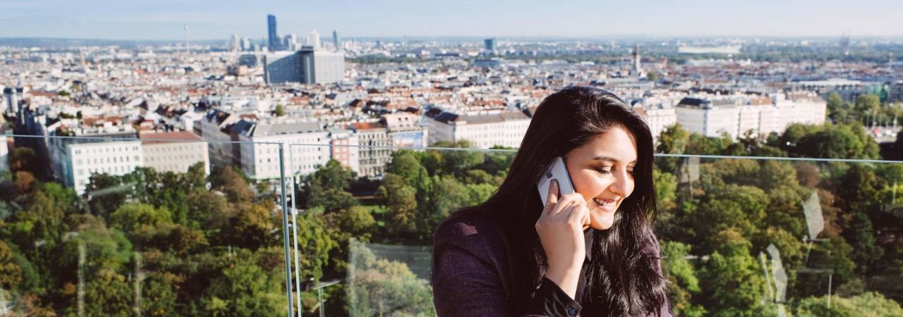 Жена, говореща по телефона на гераса с изглед към Виена
