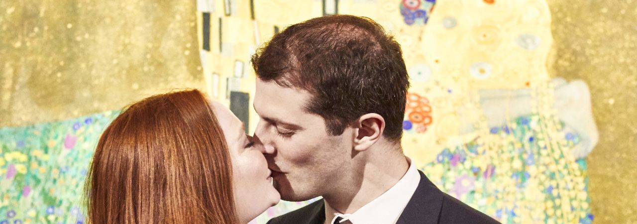 Целуващи се мъж и жена пред картината на Климт 'Целувката'