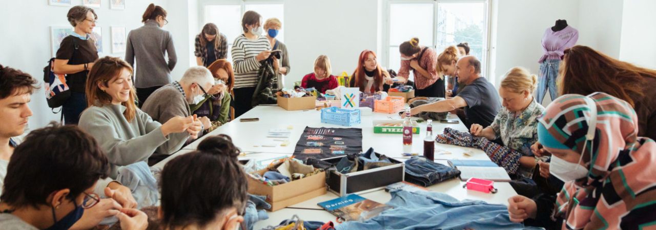 Kursteilnehmer*innen reparieren Kleidung in einem Workshop