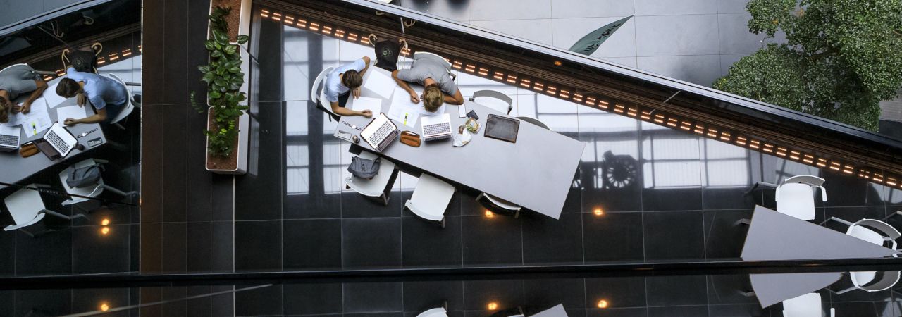 Zwei Personen arbeiten mit Laptops auf einem Tisch