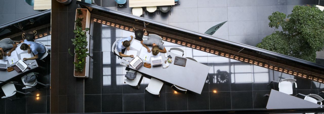 Zwei Personen arbeiten an einem Tisch mit Laptops