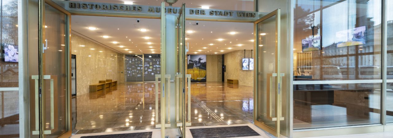 Eingang zum Wien Museum am Karlsplatz mit geöffneten Türen und taktilem Leitsystem