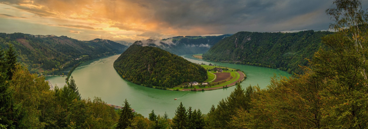 Říční zákruta o 180 stuňů řeky Dunaje v údolí zarostlém stromy